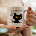 a woman holding a coffee mug with a black cat on it