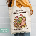 a woman holding a tote bag that says it's feels like home