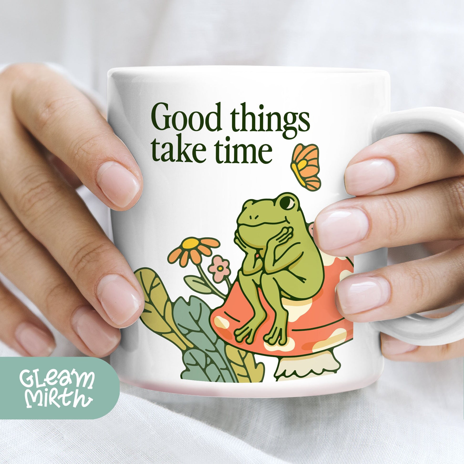 a person holding a coffee mug with a frog on it