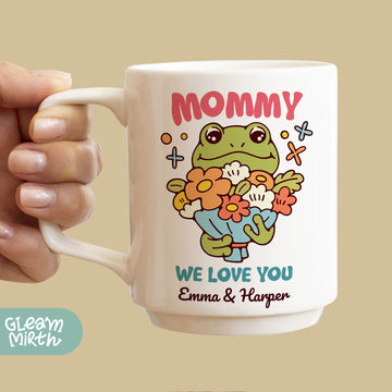 a person holding a coffee mug with a picture of a frog on it