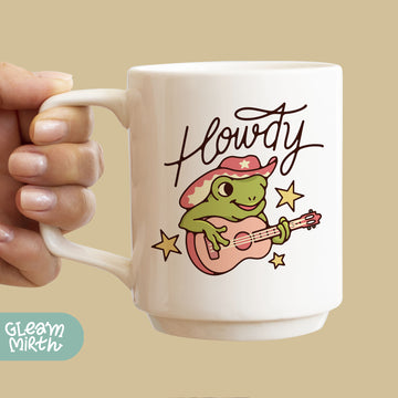 a person holding a coffee mug with a frog on it