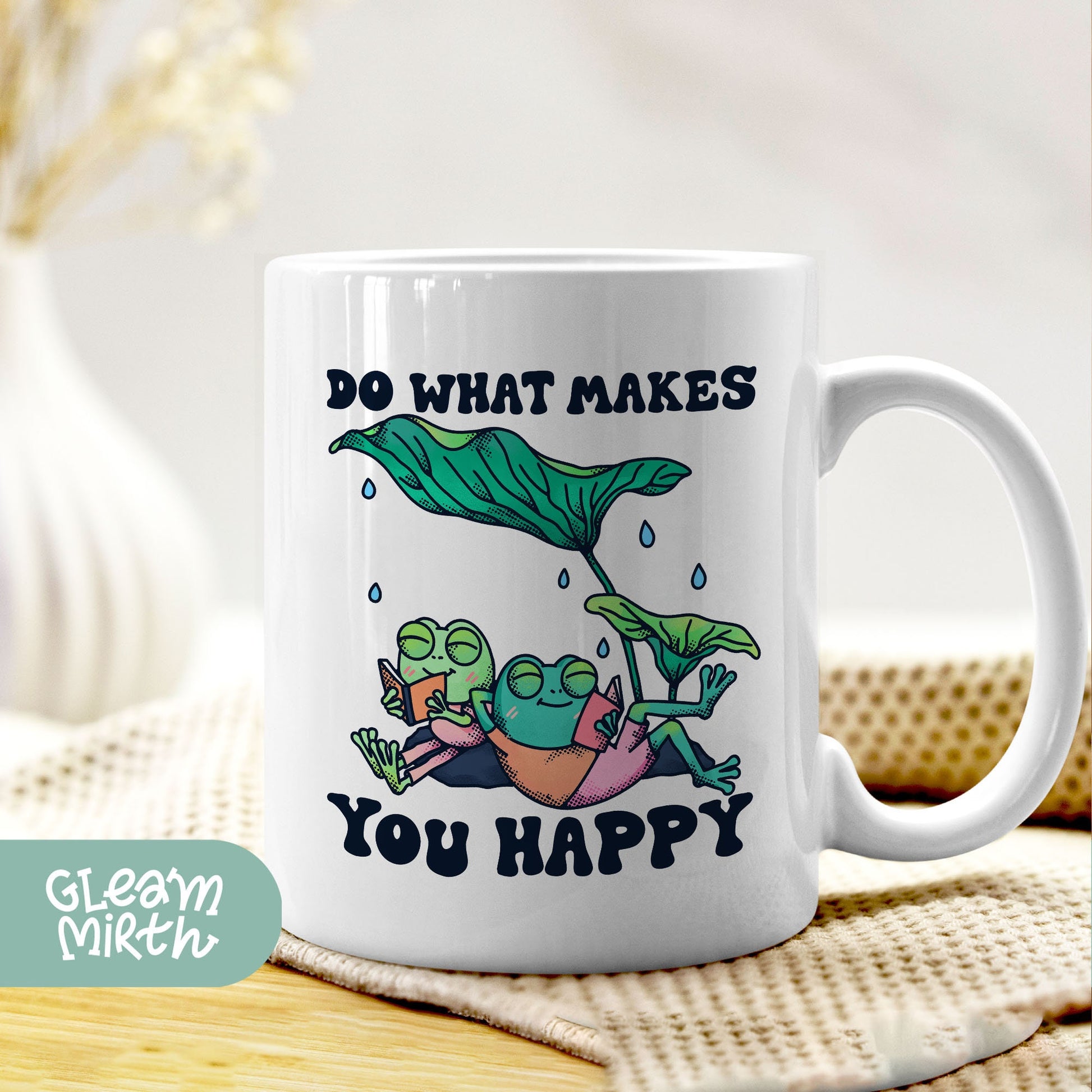 a white coffee mug with a picture of a mermaid and a frog on it