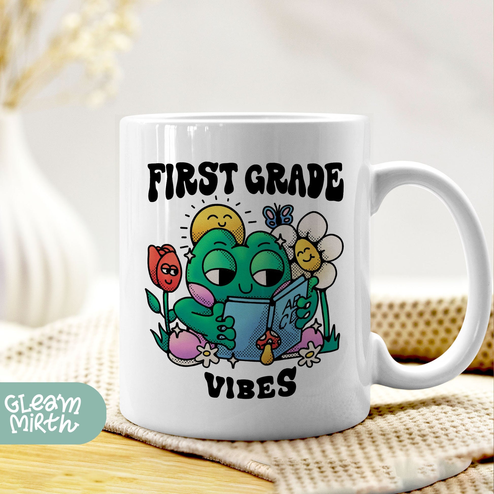 a woman is holding a coffee mug with a picture of a frog reading a book