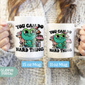 a woman holding two coffee mugs that say you can do hard things