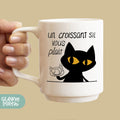 a woman holding a coffee mug with a black cat on it