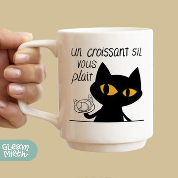 a woman holding a coffee mug with a black cat on it