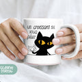 a woman holding a coffee mug with a black cat on it